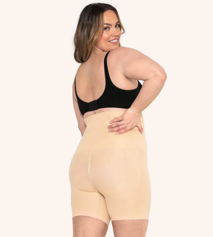 Chica voltea y sonrie mientras modela los shorts moldeadores invisibles color beige